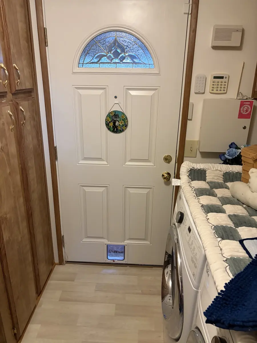 White entry door with decorative glass panel and built-in pet door, security screen door installed in front
