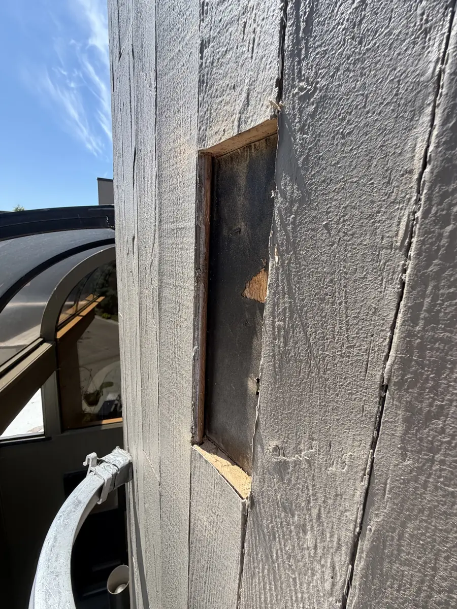 Section of exterior siding opened to reveal damaged material underneath